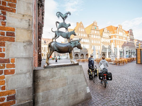 Die Bremer Stadtmusikanten auf dem Marktplatz mit historischen Gebäuden im Hintergrund