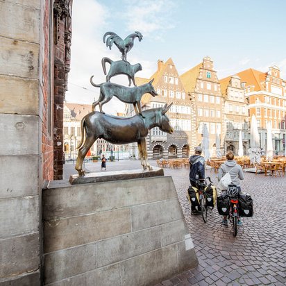 Die Bremer Stadtmusikanten auf dem Marktplatz mit historischen Gebäuden im Hintergrund