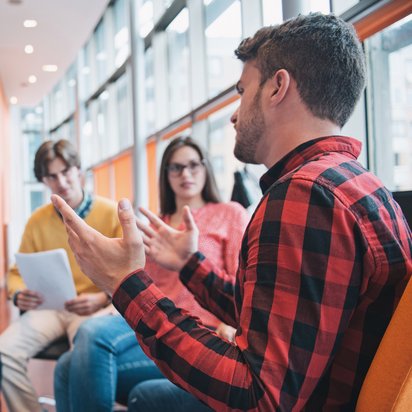 Fünf junge Erwachsene sitzen im Kreis und führen eine Besprechung.