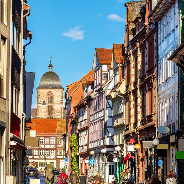 Malerische Altstadtstraße in Göttingen mit Fachwerkhäusern und dem Kirchturm im Hintergrund