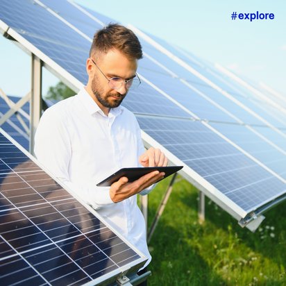 Solaranlagen-Inspektion Eine Person steht vor einer Reihe von Solarpaneelen auf einer grünen Wiese und arbeitet mit einem Tablet. Die Solarpaneele sind in einem Winkel aufgestellt, um das Sonnenlicht optimal zu nutzen.