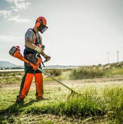 Labourer cuts a meadow with a brush cutter