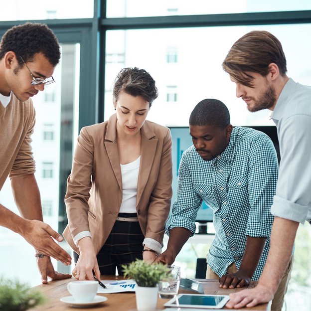 Vier Personen diskutieren konzentriert über Unterlagen auf einem Konferenztisch in einem modernen Büro.