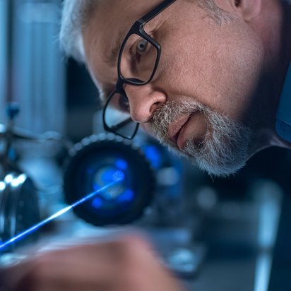 Mann prüft Produkt mit einem Laser.