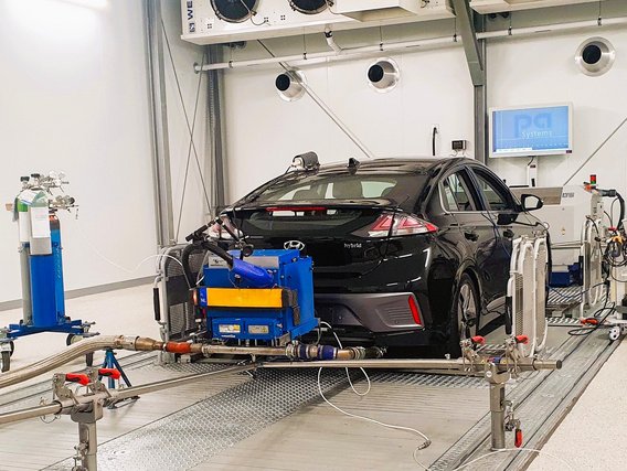 Ein schwarzer Hyundai auf einem Rollenprüfstand in der Klimakammer des TÜV NORD IFM Labors während einer präzisen Abgasmessung.