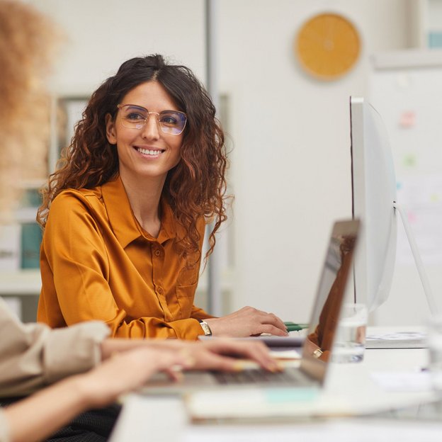 Zwei Kolleginnen im Büro arbeiten gemeinsam an ihren Laptops