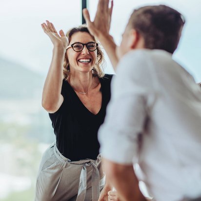 Frau und Mann in Business-Klamotten geben sich einen High-Five.