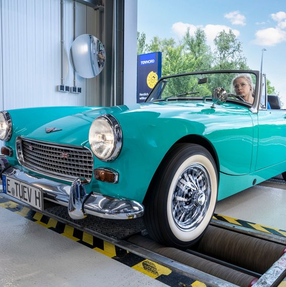 Ein türkiser Oldtimer fährt in eine TÜV NORD Station ein