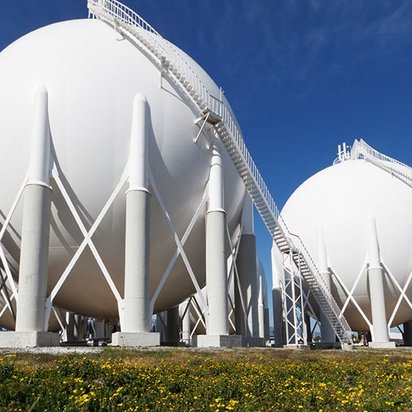 Zwei große weiße Flüssiggaslagerbehälter in Kugelform mit Außentreppen und Trägerstruktur auf einem Industrieareal.