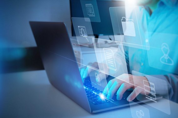 Person arbeitet an Laptop, umgeben von schwebenden digitalen Symbolen für Dokumente und Ordner.