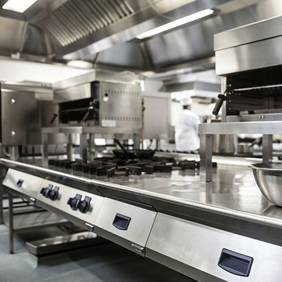 Professionelle Großküche aus Edelstahl mit Kochstationen und Lüftungsanlage – typisches Umfeld für den Einsatz von Fettabscheidern.