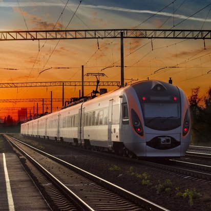Zugfahrt bei Sonnenuntergang auf der Bahnstrecke Moderner Zug bei Sonnenuntergang auf einer Bahnstrecke