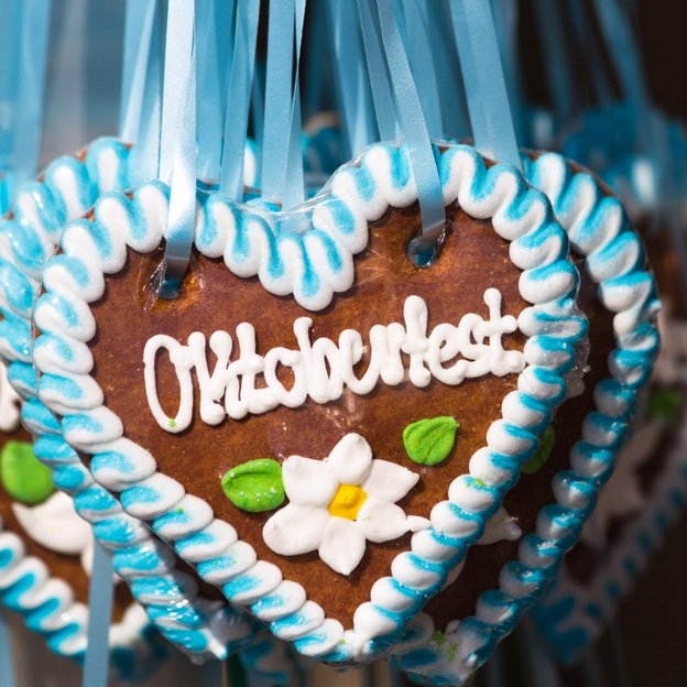 Lebkuchenherz mit blau-weißer Zuckerdekoration und Schriftzug 'Oktoberfest' im Festzelt
