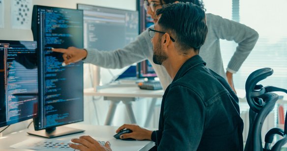 Zwei Personen arbeiten an Computercodes in einem Büro