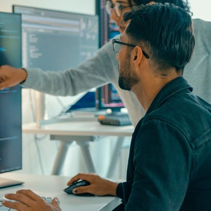 Zwei Personen arbeiten an Computercodes in einem Büro