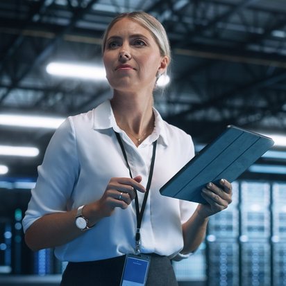 Ein Security Incident Manager steht in einem Rechenzentrum und hält ein Tablet, während sie Daten oder Systeme überprüft.