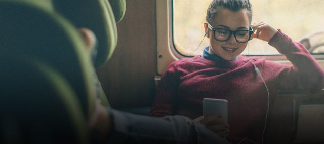 Eine junge Frau hört im Zug einen Podcast