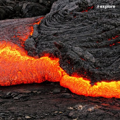 Glühend heiße, rote Lava fließt über schwarze erkaltete Gesteinsschichten und leuchtet intensiv in der dunklen Umgebung.