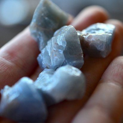 Pieces of mineral raw materials are scattered on a hand.