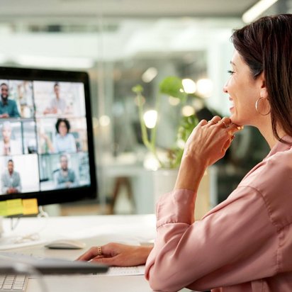 Frau nimmt an einer Videokonferenz teil und schaut auf den Bildschirm mit mehreren Teilnehmern