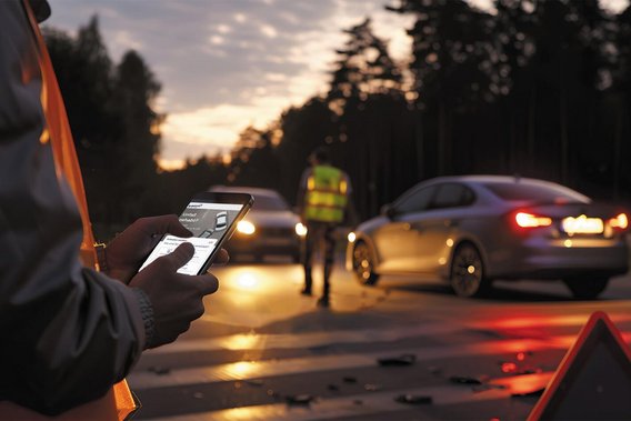 Unfallaufnahme mit Smartphone auf einer Straße bei Dämmerung