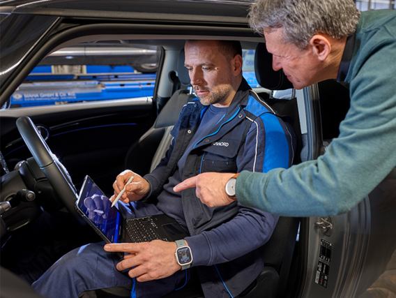 Zwei Männer im Auto mit einem Tablet in der Hand