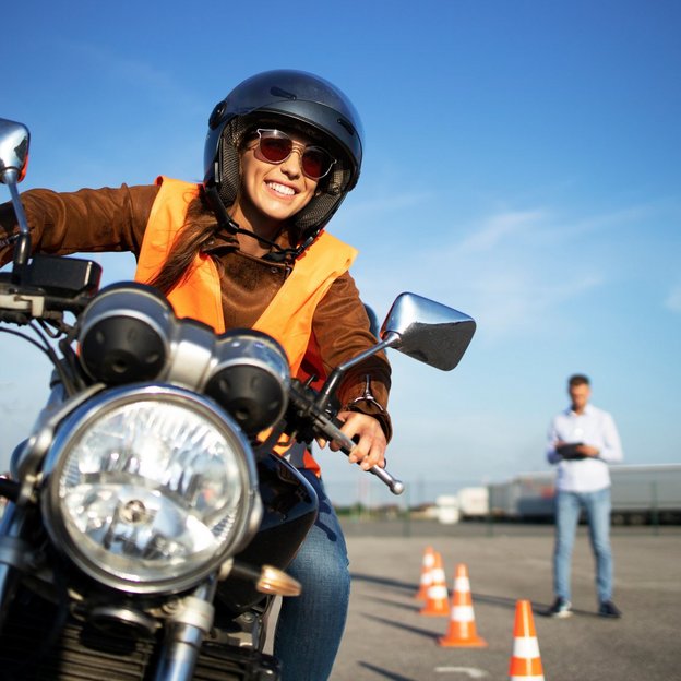 Motorradfahrer bei der Fahrprüfung mit einem Prüfingenieur im Hintergrund