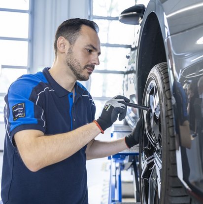 Reifeninspektion in der Werkstatt Mechaniker bei der Inspektion der Reifen eines angehobenen Fahrzeugs in einer Werkstatt.