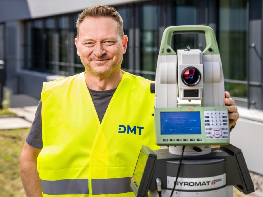 Jörg Niese in gelber DMT-Warnweste mit einem Vermessungsgerät vom Typ Pyromat 6000 im Freien.
