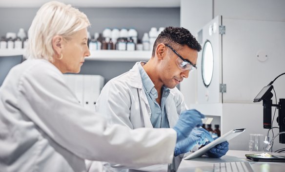 Ein Wissenschaftsteam arbeitet gemeinsam in einem Labor, betrachtet Daten auf einem Tablet