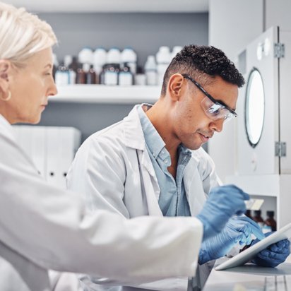Ein Wissenschaftsteam arbeitet gemeinsam in einem Labor, betrachtet Daten auf einem Tablet Ein Wissenschaftsteam arbeitet gemeinsam in einem Labor, betrachtet Daten auf einem Tablet