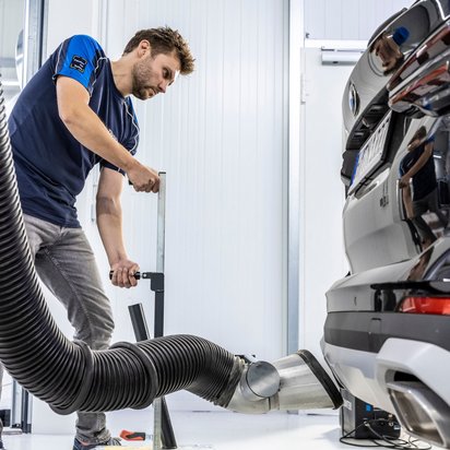 Prüfingenieur bei der Abgasuntersuchung eines Fahrzeugs an der TÜV NORD Station