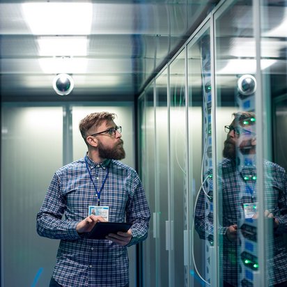 IT-Techniker mit Tablet überprüft Serverracks in einem modernen Rechenzentrum.