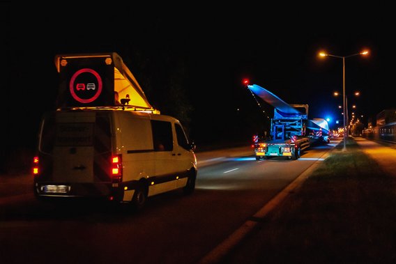 BF3 Begleitfahrzeug begleitet Schwertransport bei Nacht auf einer beleuchteten Straße