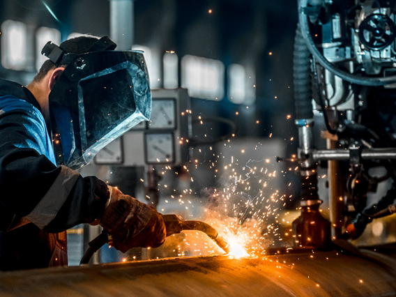 Industriearbeiter mit Schweißgerät bei der Metallbearbeitung – energieintensive Produktion mit hohem Stromverbrauch