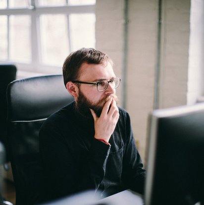 KI-Spezialist entwirft KI-Strategie Ein KI-Manager sitzt nachdenklich vor seinem Computer-Bildschirm.