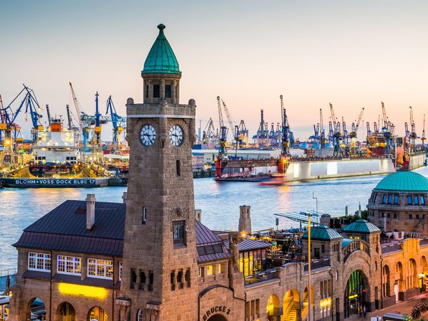 Blick auf den Hamburger Hafen mit der Landungsbrücke und großen Krähnen im Hintergrund