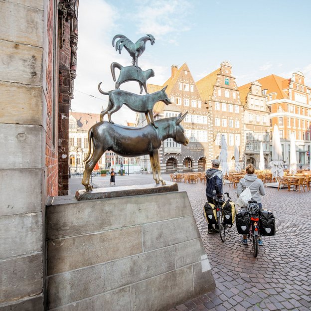 Die Bremer Stadtmusikanten auf dem Marktplatz mit historischen Gebäuden im Hintergrund
