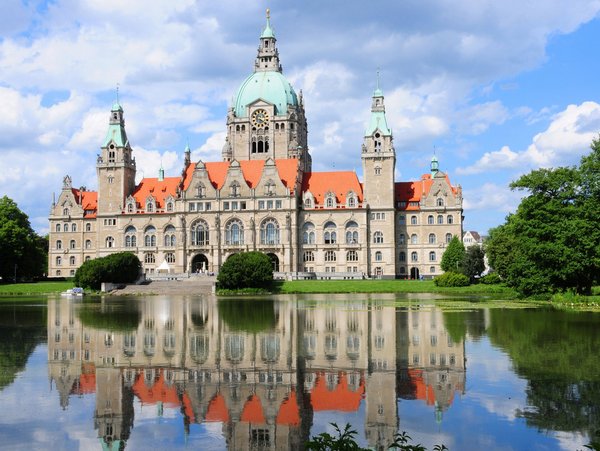 Blick auf das Neue Rathaus Hannover mit Spiegelung im Maschteich bei sonnigem Wetter