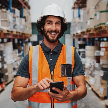 Ein Instandhaltungsmanager trägt Sicherheitskleidung und steht in einem Lagerraum