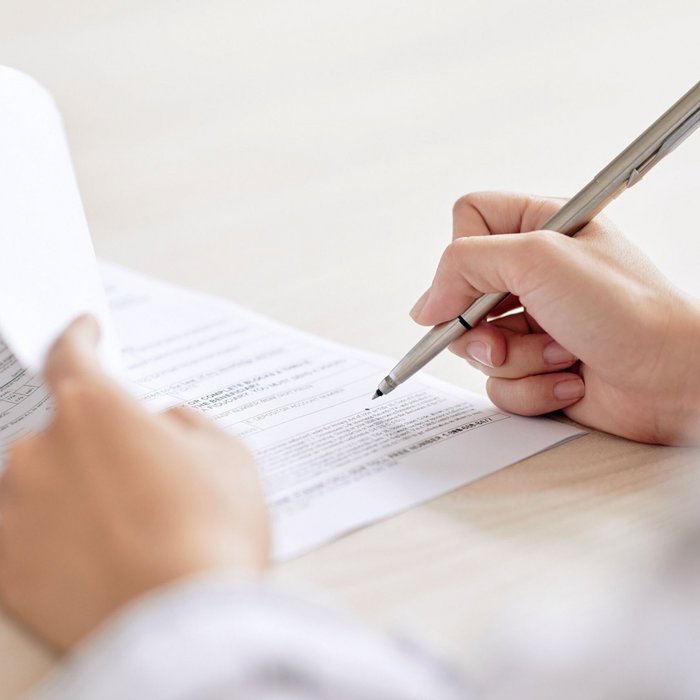 Nahaufnahme einer Hand, die einen Stift über ein Formular führt