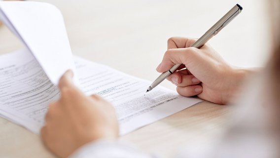 Nahaufnahme einer Hand, die einen Stift über ein Formular führt