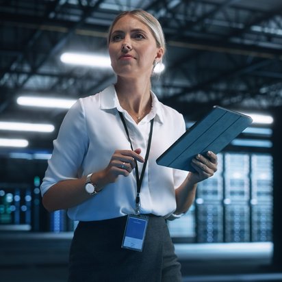 Chief Information Security Officer (TÜV) Eine Chief Information Security Officer (TÜV) steht in einem Serverraum und hält ein Tablet in der Hand