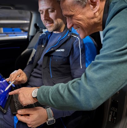 Fahrzeugprüfung an der TÜV NORD Station mit Laptop-Unterstützung Prüfingenieur und Kunde bei der Fahrzeugprüfung mit Laptop