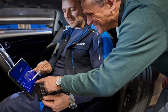 Two men in a car with a tablet in their hands