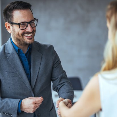 Menschenrechtsbeauftragter (TÜV) Zwei Personen stehen sich gegenüber und führen ein Gespräch in einer professionellen Umgebung.