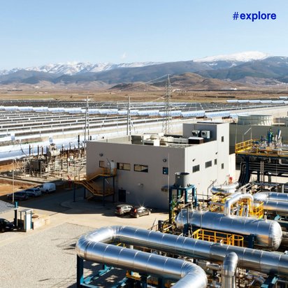 Luftaufnahme eines Solarthermiekraftwerks mit langen Reihen von Parabolspiegeln und einer Verarbeitungsanlage. Im Hintergrund sind schneebedeckte Berge unter klarem Himmel sichtbar.WiederholenClaude kann Fehler machen. Bitte überprüfen Sie die Antworten.