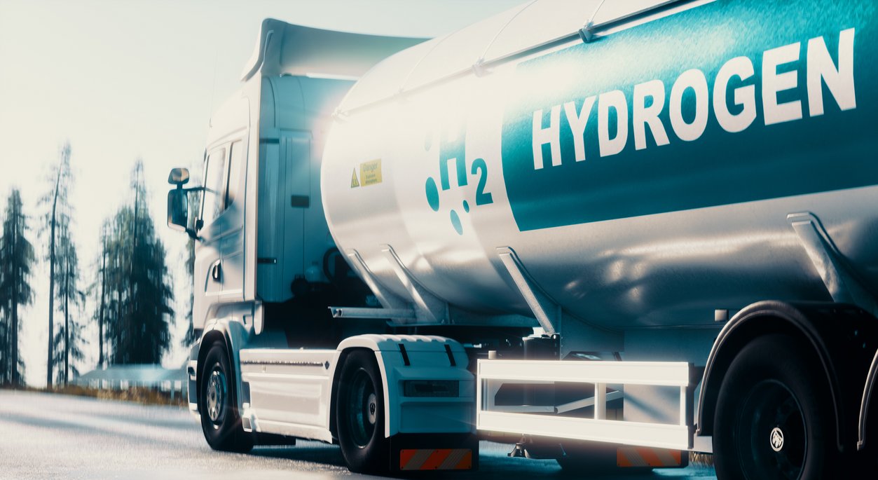 Ein weißer Tankwagen mit blauer "H2 HYDROGEN" Beschriftung, der Wasserstoff transportiert.