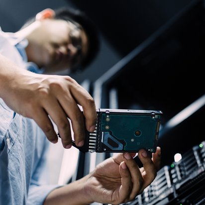 Ein Mann hält eine Festplatte in den Händen.