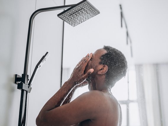 TÜV NORD_Trinkwasser_Hygiene_Dusche Junger Mann steht unter einer modernen Dusche
